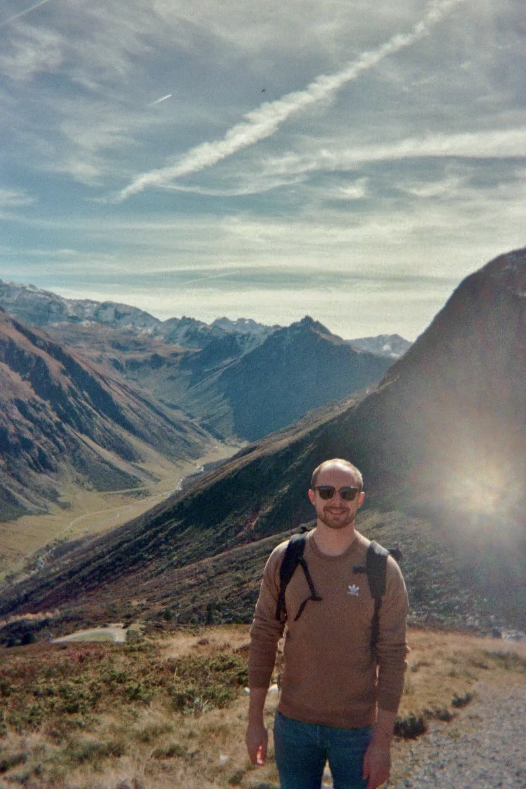 Renke Hohl hiking in the Alps, with a mountain valley behind him